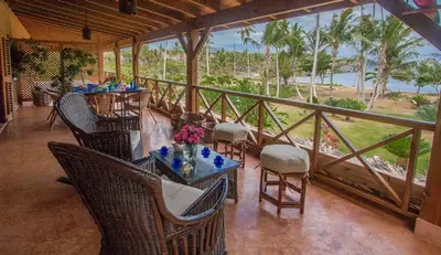 a restaurant with tables and chairs and a view of the ocean at Villa Maxime in Las Galeras
