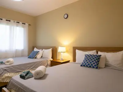 a bedroom with two beds and a clock on the wall at Soficu Hotel El Edén Dominicus in Bayahibe
