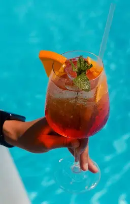 a hand holding a drink with an orange slice in it at Soficu Hotel El Edén Dominicus in Bayahibe