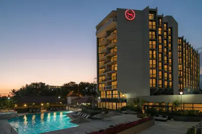 a hotel with a clock tower next to a pool at Sheraton Santo Domingo in Santo Domingo