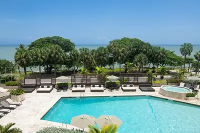 a pool with chairs and umbrellas at a resort at Sheraton Santo Domingo in Santo Domingo