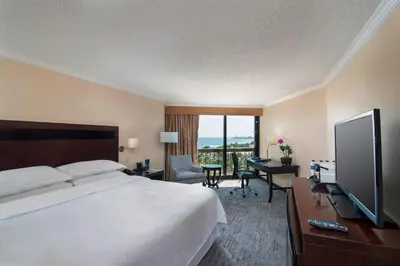 a hotel room with a bed and a desk with a television at Sheraton Santo Domingo in Santo Domingo