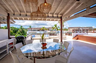 a dining room with a glass table and white chairs at Xeliter Balcones del Atlantico - Las Terrenas in Las Terrenas