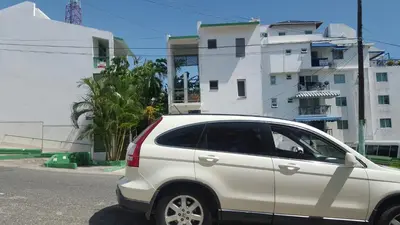 a white car parked in front of a white building at TERRAZAS DEL CARIBE, APARTA HOTEL. in Santo Domingo