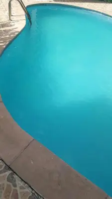 a swimming pool with blue water next to a sidewalk at TERRAZAS DEL CARIBE, APARTA HOTEL. in Santo Domingo