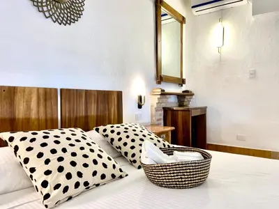 a bed with black and white pillows and a mirror at Paseo Colonial - Sanctuary #2 in Santo Domingo