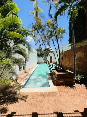 a swimming pool with palm trees next to a building at Paseo Colonial - Ermitage #5 in Santo Domingo