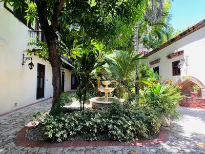 a courtyard with trees and plants in front of a building at Paseo Colonial - Ermitage #5 in Santo Domingo