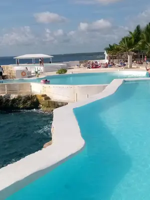 a swimming pool with blue water next to a beach at Apartamentos y habitaciones sol dominicus SOLO ADULTOS in La Laguna