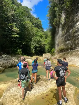 a group of people crossing a river near a waterfall at Surfbreak B&B in Cabarete