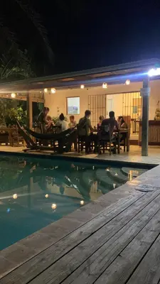 a group of people sitting around a table by a swimming pool at Surfbreak B&B in Cabarete