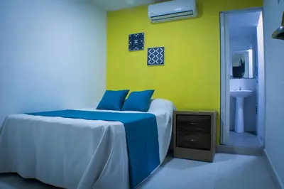 a bedroom with a bed and a yellow wall at Malecon Rooms y Hotel in Santo Domingo