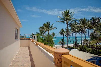 a balcony with a view of the beach and palm trees at Kite Beach Inn in Cabarete