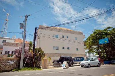 a white building with cars parked in front of it at Kite Beach Inn in Cabarete