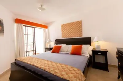 a bedroom with a bed with orange pillows and a window at Sosua by the Sea in Sosúa
