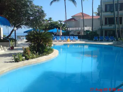 a large blue swimming pool with chairs and a building at Sosua by the Sea in Sosúa