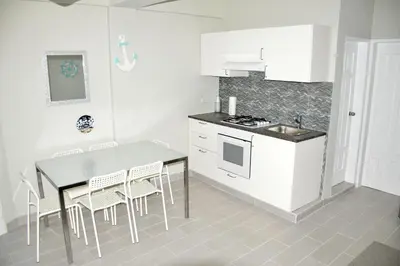 a kitchen with white cabinets and a table and chairs at Caribe Apartament S&D el castillo dominicus Apartamento #9 in Bayahibe