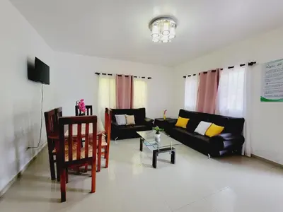 a living room with a black couch and a table at Oasis de paz in Jarabacoa