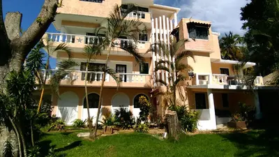 a large building with palm trees in front of it at Hotel Coco Plaza in Las Terrenas