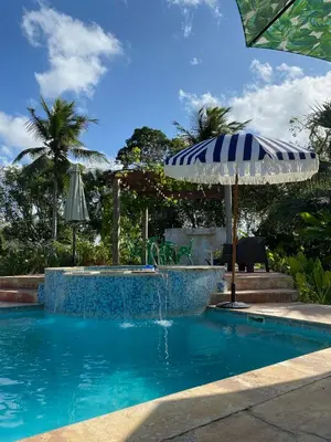 a swimming pool with an umbrella and a fountain at Campito Loving in Higuey