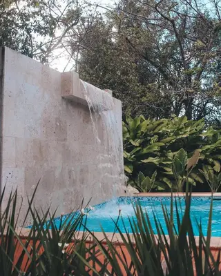 a retaining wall next to a pool with a water fountain at Campito Loving in Higuey