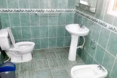 a green tiled bathroom with a toilet and a sink at Elegant Villa in Nagua with Private Pool and Jacuzzi in Nagua