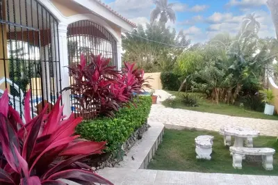 a garden with pink plants and a bench in front of a building at Elegant Villa in Nagua with Private Pool and Jacuzzi in Nagua