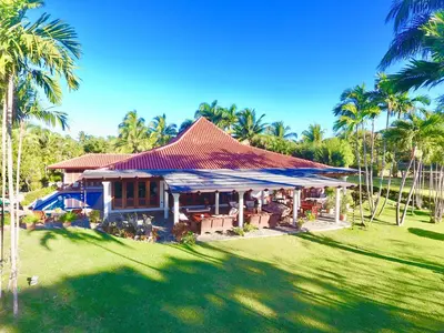 a house with a red roof and a yard with palm trees at CASA NOSTRA RESORT by Klabhouse in La Romana