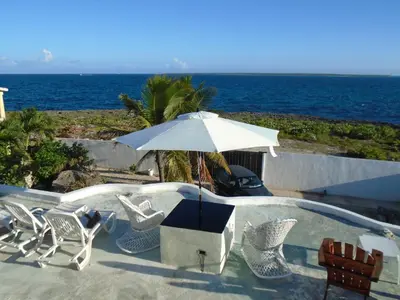 a pool with chairs and an umbrella next to the ocean at Guesthouse Villa La Isla in La Romana