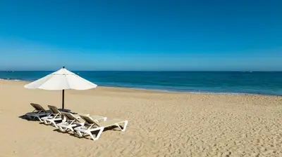 two lounge chairs and an umbrella on a beach at Blue JackTar in San Felipe de Puerto Plata