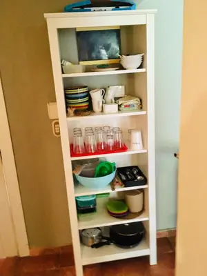 a white pantry shelving unit with bowls and dishes at bungalow 3116 vue sur piscine in Las Galeras