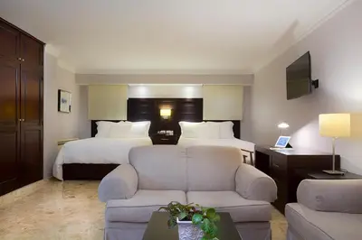 a hotel room with two beds and a couch at Plaza Florida Suites in Santo Domingo