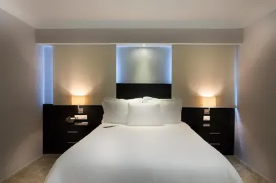 a bedroom with a large white bed with two lamps at Plaza Florida Suites in Santo Domingo