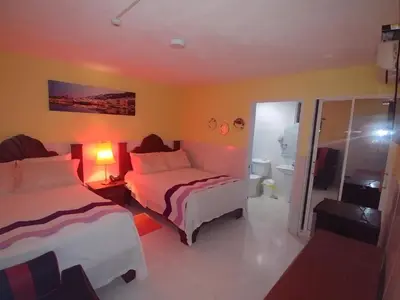 a hotel room with two beds and a bathroom at Hotel Riparbella in Santo Domingo