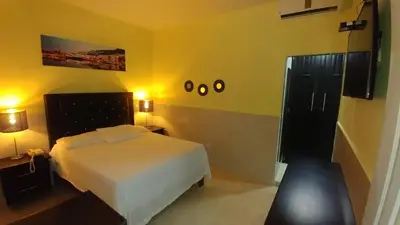 a bedroom with a white bed and yellow walls at Hotel Riparbella in Santo Domingo