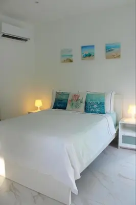 a white bed in a white room with two lamps at Villa Luce in Las Terrenas
