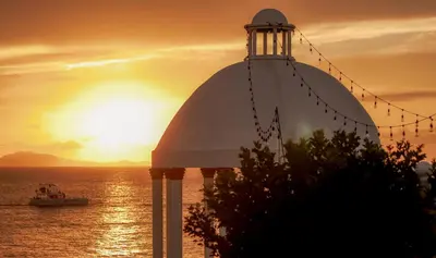 a lighthouse with a boat in the ocean at sunset at Piergiorgio Palace Hotel in Sosúa