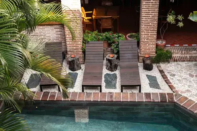 a swimming pool with wooden stairs next to a house at Hotel Villa Colonial in Santo Domingo