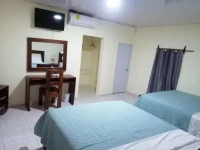a bedroom with two beds and a desk and a mirror at Hotel Anedi in Concepción de La Vega
