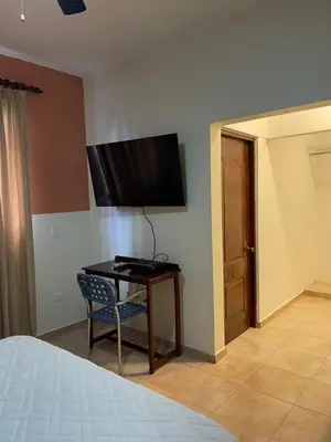 a bedroom with a table and a tv on the wall at Apartahotel Alvear in Santo Domingo