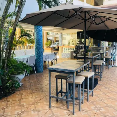 a patio with tables and chairs and an umbrella at Hotel La Casona Dorada in Santo Domingo