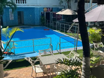 a large blue swimming pool with chairs and an umbrella at Hotel La Casona Dorada in Santo Domingo