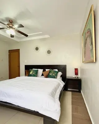 a bedroom with a large white bed with a ceiling fan at Aparta Hotel Roma in Santo Domingo