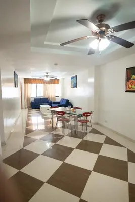 a living room with a ceiling fan and a table and chairs at Aparta Hotel Roma in Santo Domingo