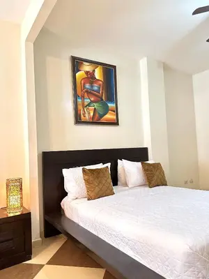 a bed in a bedroom with a painting on the wall at Aparta Hotel Roma in Santo Domingo