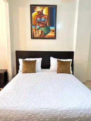 a bedroom with a white bed with a painting on the wall at Aparta Hotel Roma in Santo Domingo