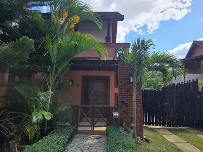 a house with palm trees in front of a fence at Ximenoa Rivers Villa Relax in Jarabacoa