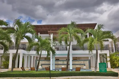 a building with palm trees in front of it at Sybaris Suites & Residences in Juan Dolio