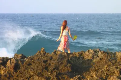 a woman walking on the rocks near the ocean at Beachfront apartment near Cabarete in Cabarete