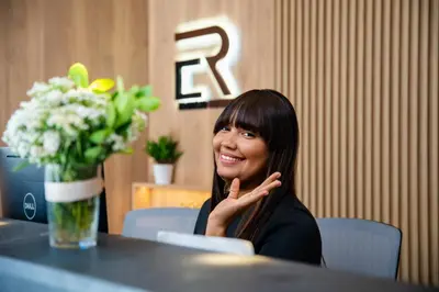 a woman sitting at a table with a vase of flowers at Apartamentos Roman in Santo Domingo